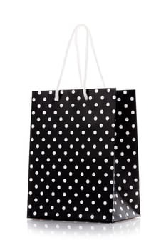 Shopping bag. Black package for shopping or gifts with white handles and dots. Concept of gifts for birthday, women's day, mother's day. Isolated on white.