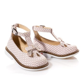Pair of stylish elegant sandals for little girl isolated on white background. Pink shoes with white dots and bow. Children's fashion concept. Copy space.