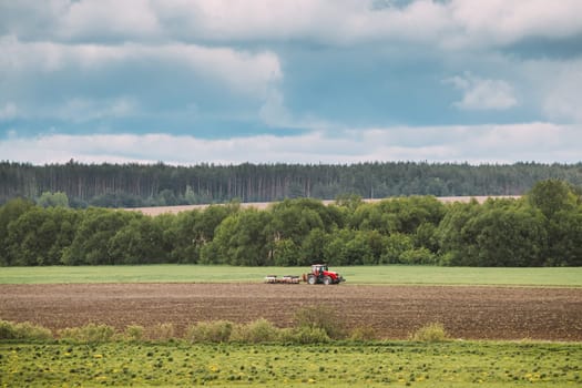 Tractor Plowing Field In Spring Season. Beginning Of Agricultural Spring Season. Cultivator Pulled By A Tractor In Countryside Rural Field. Countryside Rural Field Landscape.