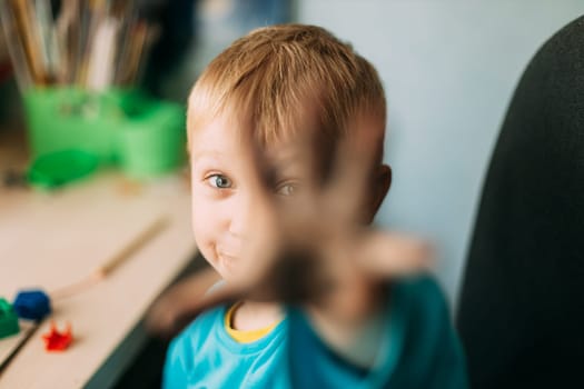 Little Blond Boy Shows His Hand Stained With Paint.