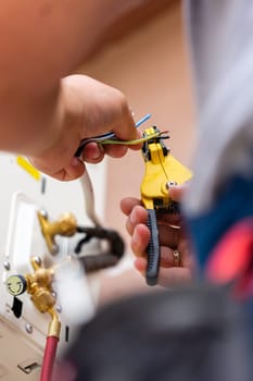Close up of hands of male engineer-assembler working with outdoor air conditioner unit. Air conditioning repair technician works on street, installs fasteners and connects wires.