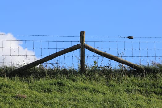 Part of a pasture fence, blue sky in the background.Teilstück eines Weidezaunes, blauer Himmel im Hintergrund.