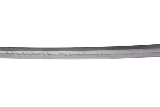 Japanese sword blade (made in China) on white background. Soft focus. The wavy pattern on the blade edge is a line of hardness that a blacksmith makes so that the blade doesn't break.
