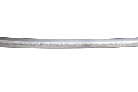 Japanese sword blade (made in China) on white background. Soft focus. The wavy pattern on the blade edge is a line of hardness that a blacksmith makes so that the blade doesn't break.