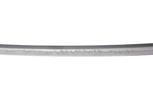 Japanese sword blade (made in China) on white background. Soft focus. The wavy pattern on the blade edge is a line of hardness that a blacksmith makes so that the blade doesn't break.