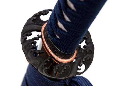 Wave Design Tsuba: Japanese sword hand guard made of steel. Sword hilt and sheath wrapped with navy cord, black scabbard, isolated on white background.