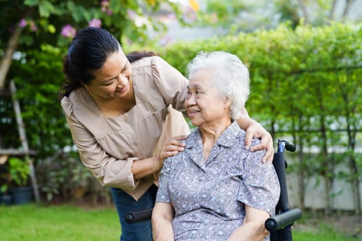 Caregiver help Asian elderly woman disability patient sitting on wheelchair in park, medical concept.
