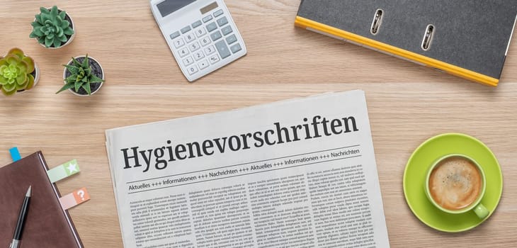 A newspaper on a desk with the headline Hygiene Regulations in german - Hygienevorschriften
