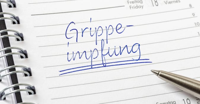 Influenza Vaccination written on a calendar page in german - Grippeimpfung