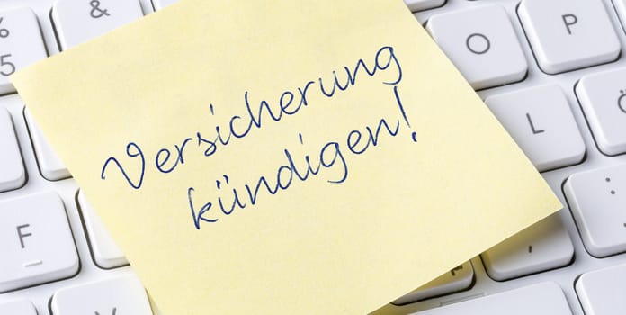 Sticky note on a keyboard - Cancel insurance in german - Versicherung kündigen