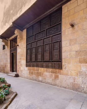 Wooden arabesque window, Mashrabiya, and door in exterior stone bricks wall of ottoman era old historic El Sehemy building, Moez Street, Cairo, Egypt