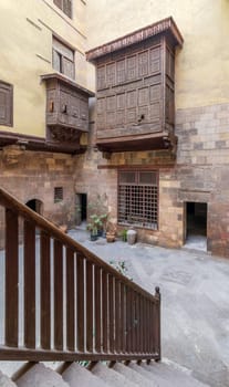 Staircase with wooden balustrade revealing facade of ottoman era historic house of El Sehemy with wooden oriel windows - Mashrabiya - located at Moez Street, Cairo, Egypt