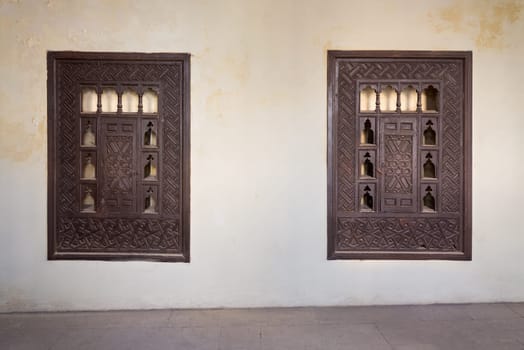 Two wooden arabesque ottoman era cupboards with engraved decorations embedded in a grunge wall