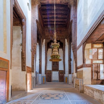 Hall at ottoman era historic house of Zeinab Khatoun with painted wooden ceiling, marble floor decorated with colorful geometric patterns, and big chandelier, Medieval Cairo, Egypt