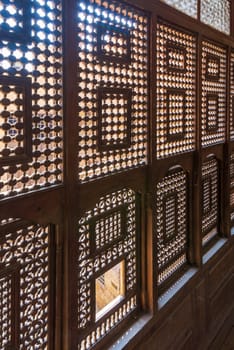 Angle view of interleaved wooden ornate windows - Mashrabiya - in stone wall at abandoned building