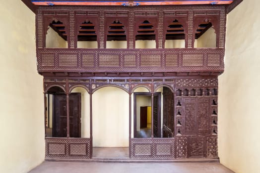 Oriental wooden engraved arabesque decorations with balcony installed in front of open doors inside empty spacious room