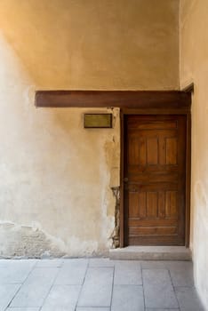 Wooden aged door on grunge stone wall and blank weathered copper door sign, Medieval Cairo, Egypt