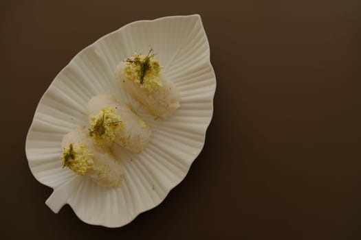 Plate with traditional Japanese onigiri with egg on brown background and beautiful white plate with leaf shape.