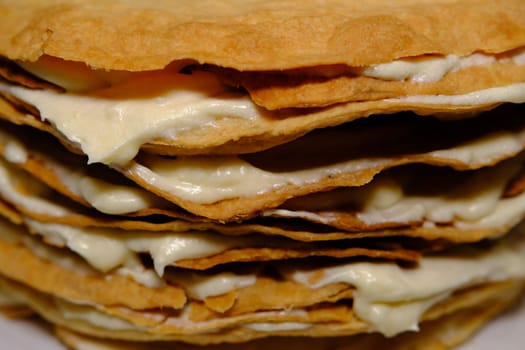 Puff pastry cake Napoleon layers closeup texture with white cream inside.