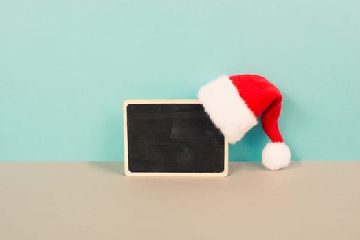 Red Santa Claus hat hanging on a chalkboard, greeting card for christmas, copy space for text, winter season
