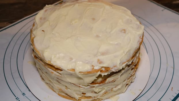 Man's hand levels cream on cake, cake decor. Making Napoleon cake with cream.