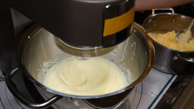 Male hands add the ingredient cream for baking in the bowl of a food processor. Crash with paddle adding cream. Safety first.