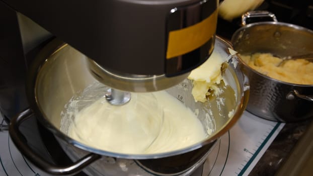 male hands add the ingredient cream for baking in the bowl of a food processor