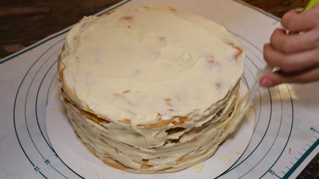 Man's hand levels cream on cake, cake decor. Making Napoleon cake with cream.