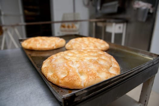 Elaboration process of traditional spanish olive oil pancakes. Baker taking fresh baked pancakes from oven