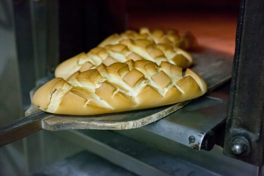 baking peel taking fresh baked bread from oven. Manufacturing process of spanish bread