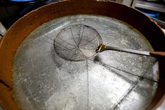 Skimmer driping oil over sieve. Used for cooking with fried food