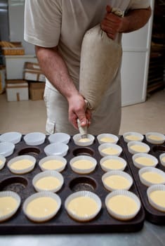 Baking cups being piped. Handmade manufacturing process of spanish madeleines