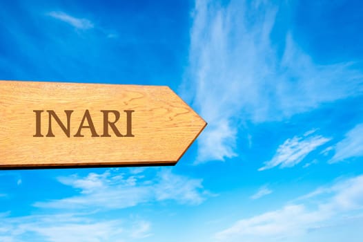 Wooden arrow sign pointing destination INARI, FINLAND against clear blue sky with copy space available. Travel destination conceptual image