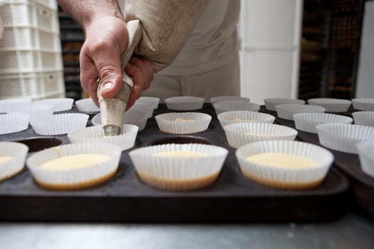 Baking cups being piped. Handmade manufacturing process of spanish madeleines