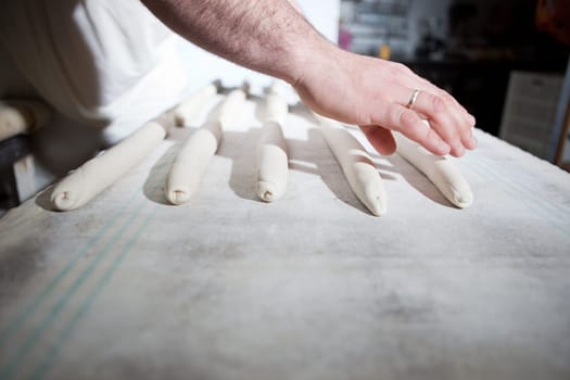 Male baker kneading raw pieces of bread. Manufacturing process of spanish bread