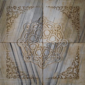 Traditional Mamluk era round geometrical patterns framed by floral patterns carved into an exterior marble wall of public ancient mosque of Sultan Al Moaayad, Old Cairo, Egypt