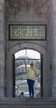 Istanbul, Turkey - April 16 2017: Female tourist taking a selfie photo in front of one of the entrances of the Blue Mosque - Sultan Ahmed Mosque