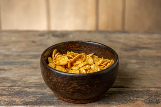 Cereal in wooden bowl with milk splash on blurred wooden background