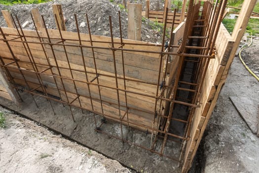 Tied rebar and mounted formwork close-up before pouring the strip foundation when building a house