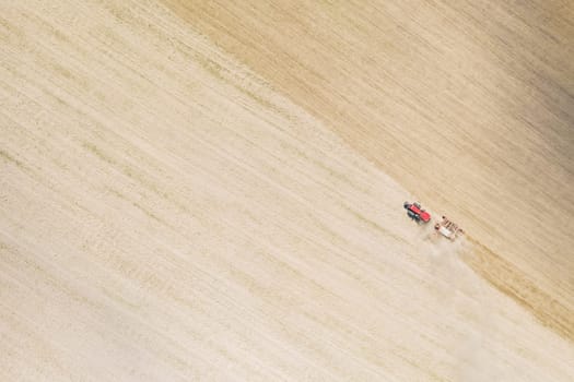 Aerial View. Tractor With Seed Drill Machine Sowing The Seeds For Crops In Spring Season. Beginning Of Agricultural Spring Season. Countryside Field Landscape. Natural Rural Background.