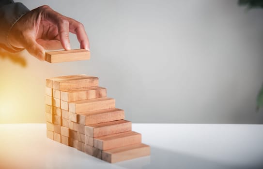 Business hand arranging put wooden block stacking step stair growth success process, financial risk management and strategic plan and business challenge planning concept, prevent collapse or crash