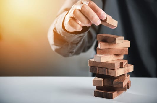 Alternative risk plan. Business hand playing tower wooden blocks game, man pull one wood block from tower he clenched his fist, show great joy in accomplishing it, Business gambling growth concept