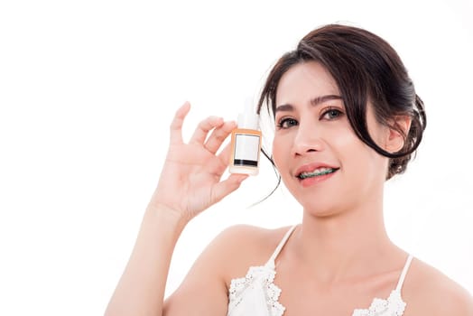 Asian young beautiful woman smiling she's holding bottle serum hair or skin care near face for present product isolated on over white background, Beauty salon concept