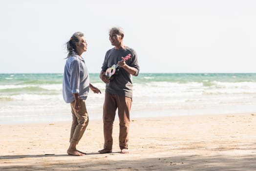 Happy senior couple relaxing outdoors singing and playing acoustic guitar at beach near sea sunny day, Mature man playing ukulele for his wife at sea, plan life insurance at retirement couple concept