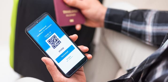 Vaccination passport, Traveler man holding health passport of vaccination certification on smartphone app at airport before boarding plane during coronavirus pandemic, Mobile app of virus COVID-19