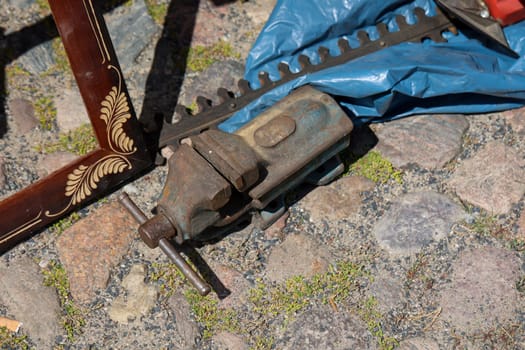 An age large vice stands on a paved floor.