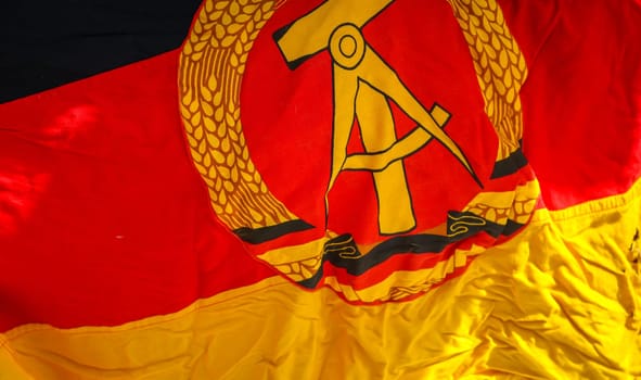 A piece of the flag of the former GDR with emblem, hammer, compass, ear wreath.