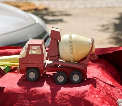 On a table is a red and yellow toy car, a concrete mixer truck. Toys for children.