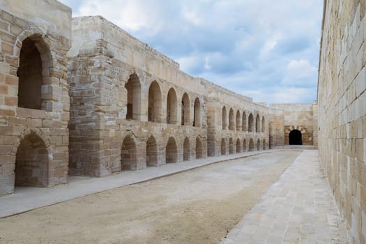 Aged building of stone blocks with archs and windows on cloudy day