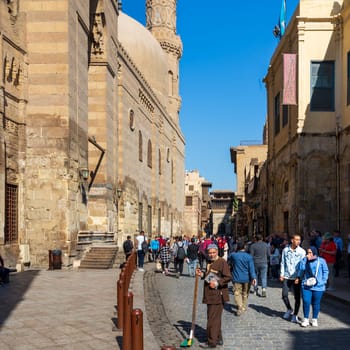 Cairo, Egypt- November 23 2019: Moez Street with local visitors Mosque of Sultan Barquq and Sabil-Kuttab of Katkhuda historic building at the far end, Gamalia district, Old Cairo